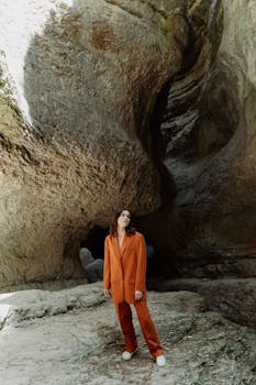 Chic fashion in earthy rock landscape, prominent orange suit stands out.