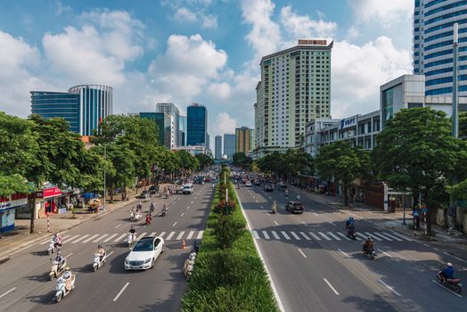 Aerial view of a bustling urban street with traffic, skyscrapers, and greenery.