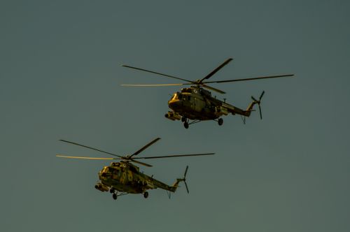 Free A pair of camouflage military helicopters flying against a clear blue sky. Stock Photo
