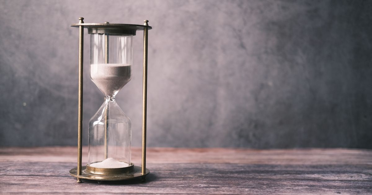 A classic hourglass on a rustic wooden table, representing the strict time window of the ICT Silver Bullet setup