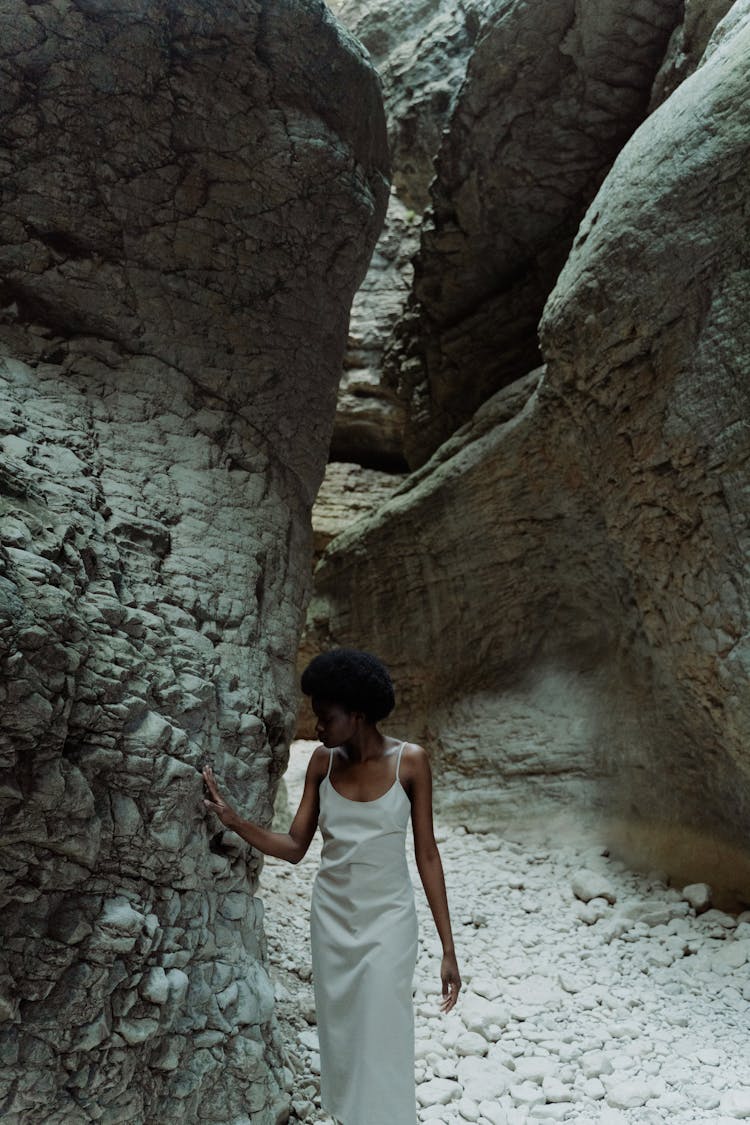 Woman In White Dress Touching The Cave Wall 