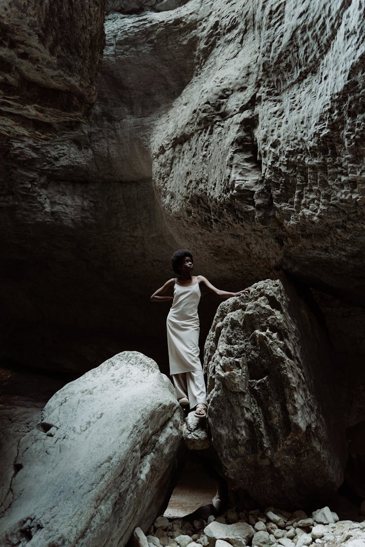 Woman Standing On A Boulder In A Cavern 