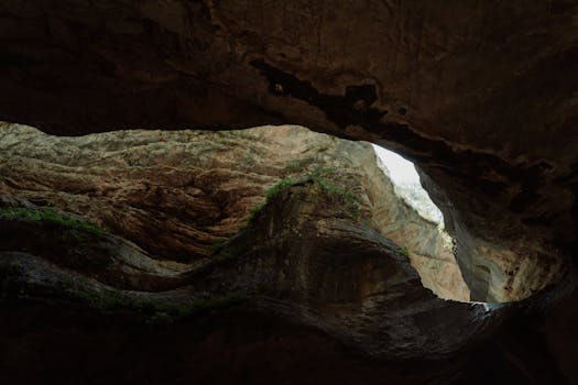 A breathtaking view of a limestone cave featuring a natural skylight and rugged textures.