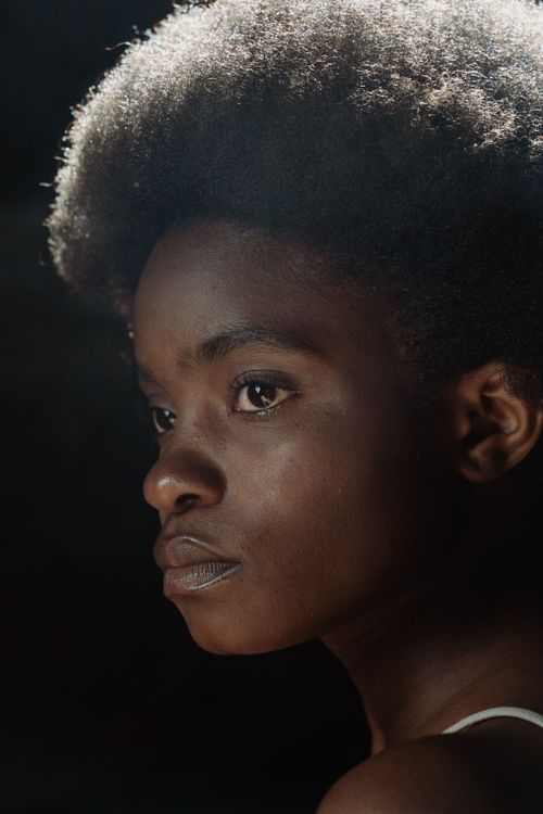 Free Captivating close-up portrait of a young black woman with afro hair, exuding confidence and beauty. Stock Photo
