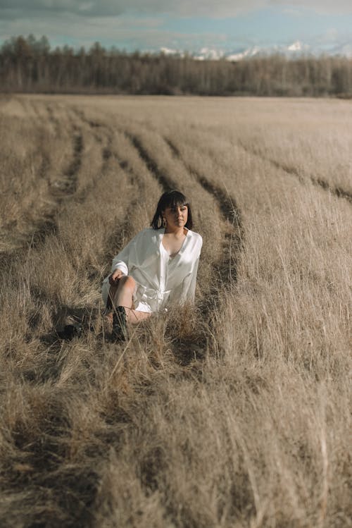 Beautiful Woman in White Dress Shirt sitting on Grass