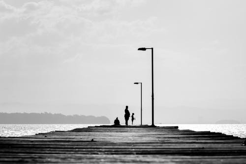 Monochrome Photo of People on wooden Jetty