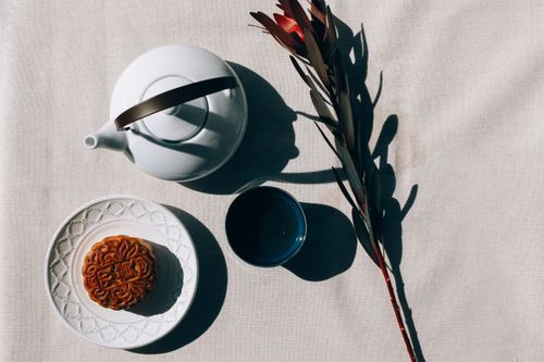 Free Flat lay of a mooncake with tea set and floral decor, ideal for Mid-Autumn Festival themes. Stock Photo