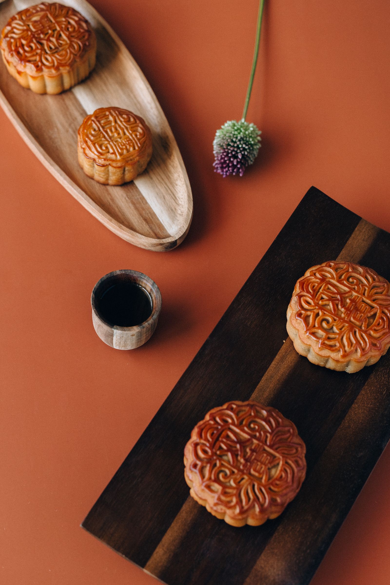Baked mooncakes on wooden trays beside a cup of tea. Photo: Nataliya Vaitkevich / Pexels.
