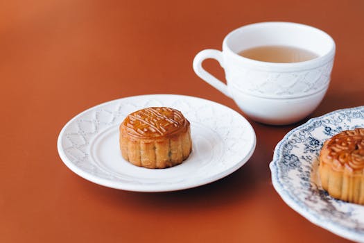 Close-up of traditional mooncakes served on white ceramic plates with a cup of tea, perfect for Mid-Autumn Festival.