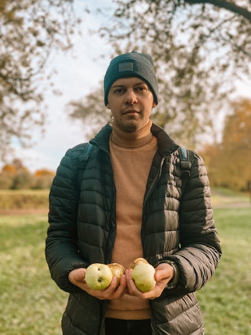 A Man in Black Puffer Jacket Holding a Fruits