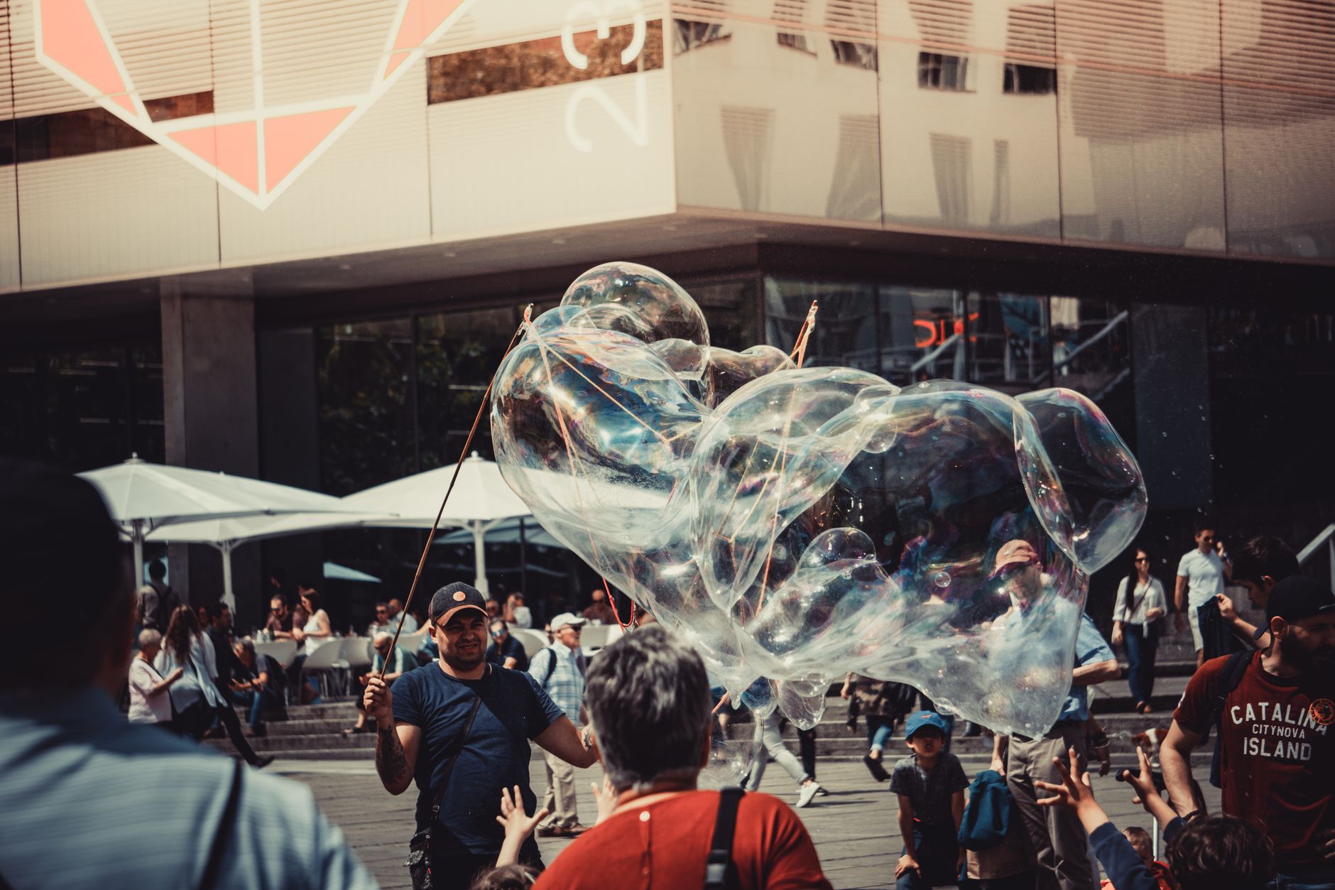 A street performer entertaining a crowd with giant soap bubbles in a bustling urban area.