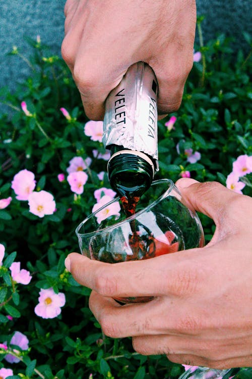 A Person Pouring Wine on a Clear Glass