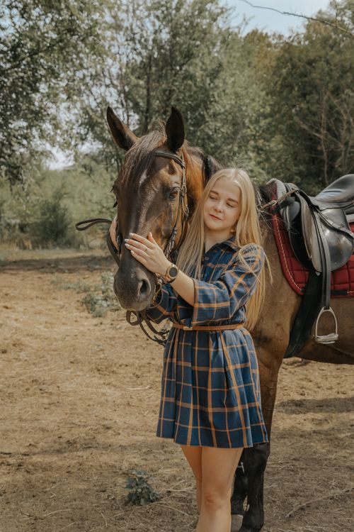 Free A young woman with long blond hair embraces a brown horse outdoors, expressing a tranquil bond. Stock Photo