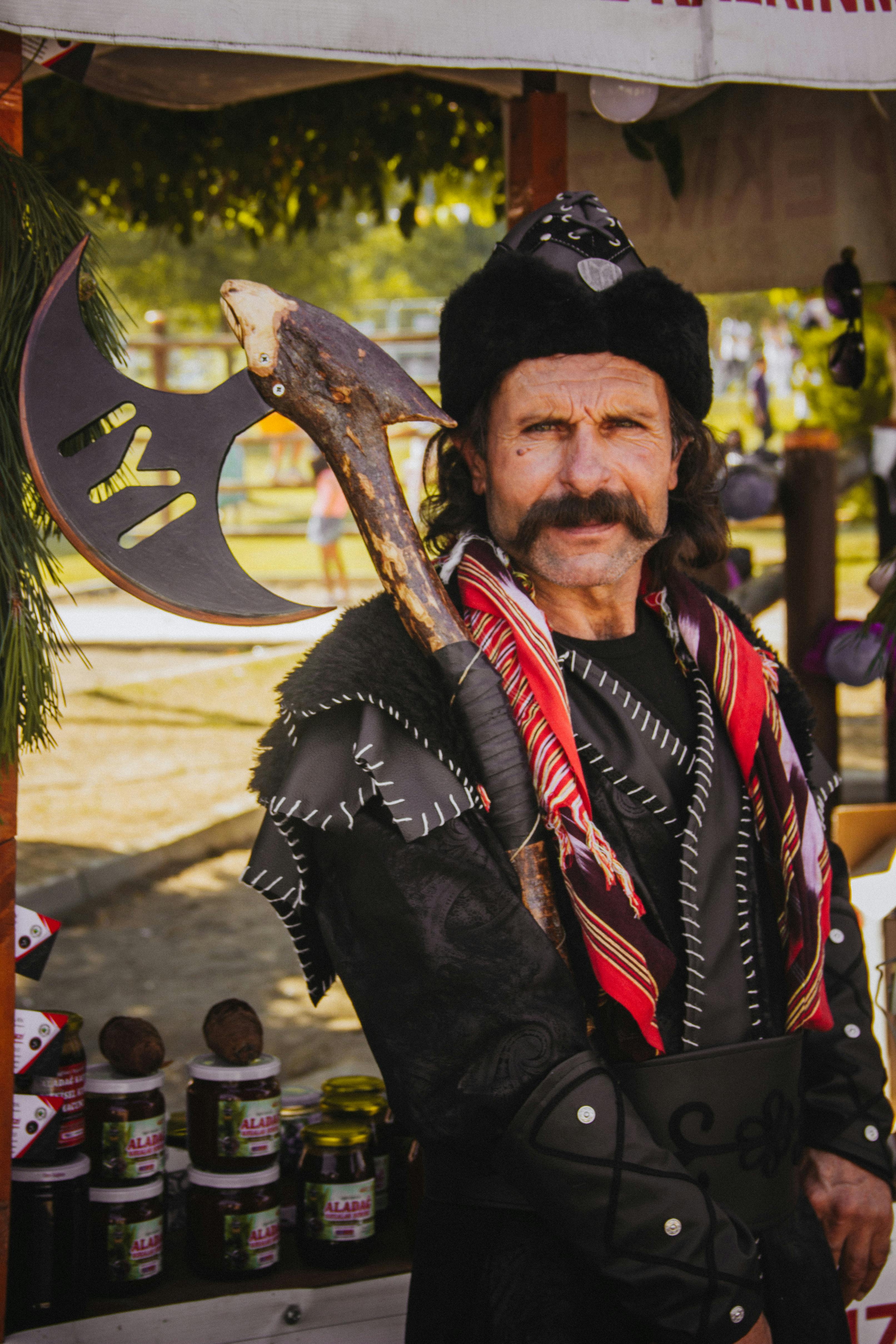 Portrait of a man in a historical costume holding an axe at a festival market.