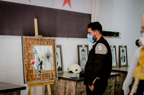 Free A man wearing a face mask observes artwork on display indoors in Idlib, Syria. Stock Photo