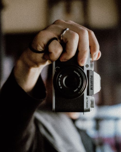 Free Artistic shot focusing on a hand holding a vintage-style camera with blurred background. Stock Photo