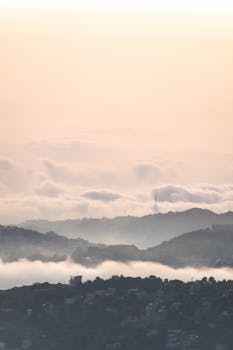 A tranquil mountain landscape captured at sunrise with clouds blanketing the valleys, creating a serene and peaceful atmosphere.