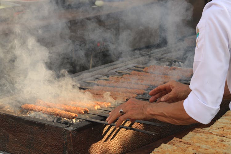 Person Grilling Kebabs 