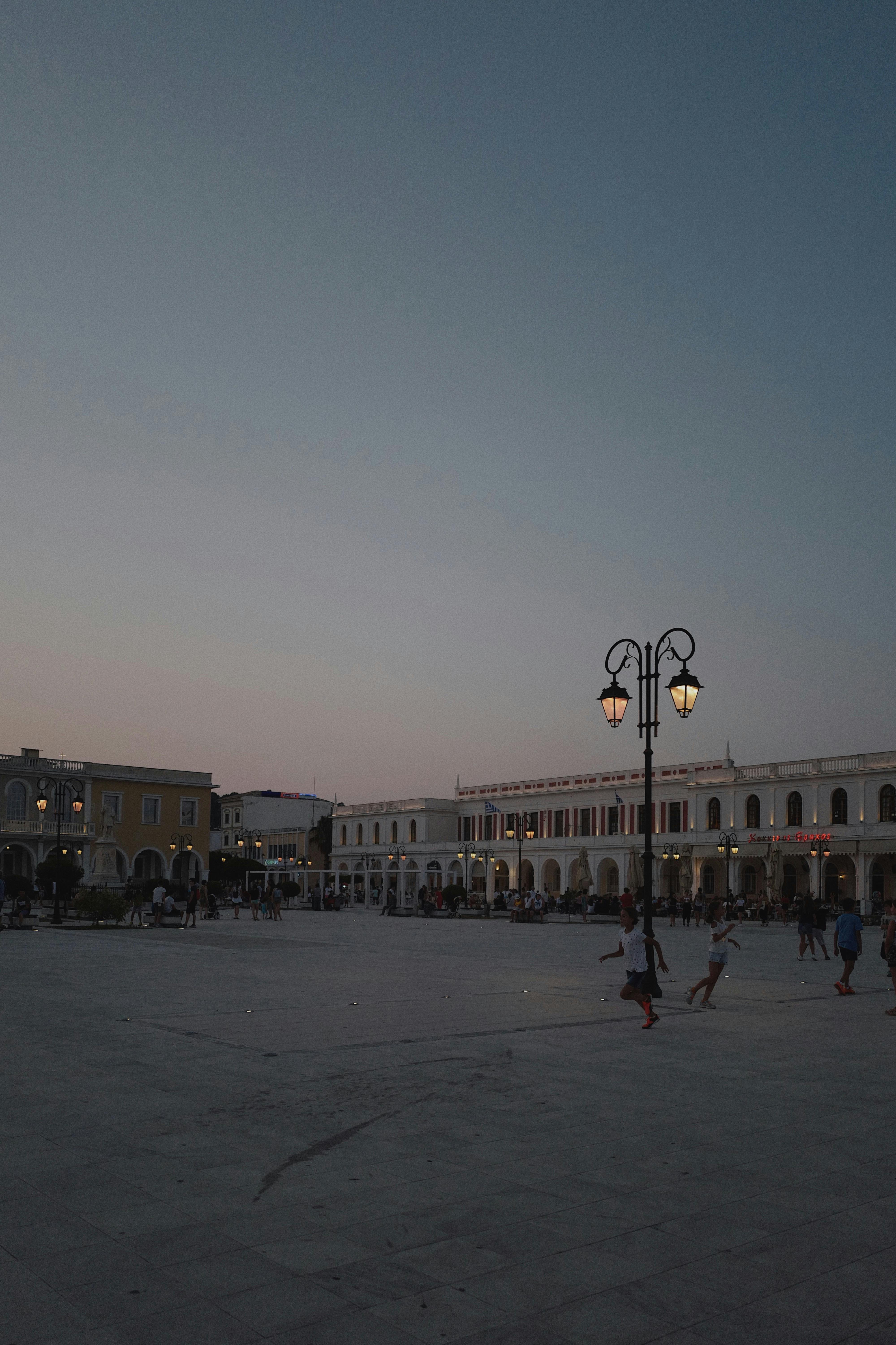 Charming outdoor plaza at twilight featuring elegant lampposts and lively atmosphere, perfect for urban exploration.
