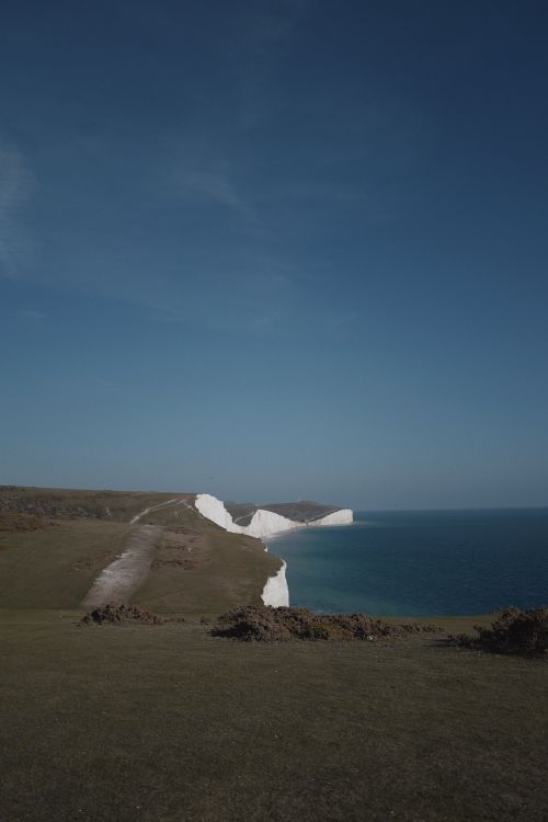 Free Stunning coastal cliffs against a clear blue sky at daytime, perfect for nature lovers. Stock Photo