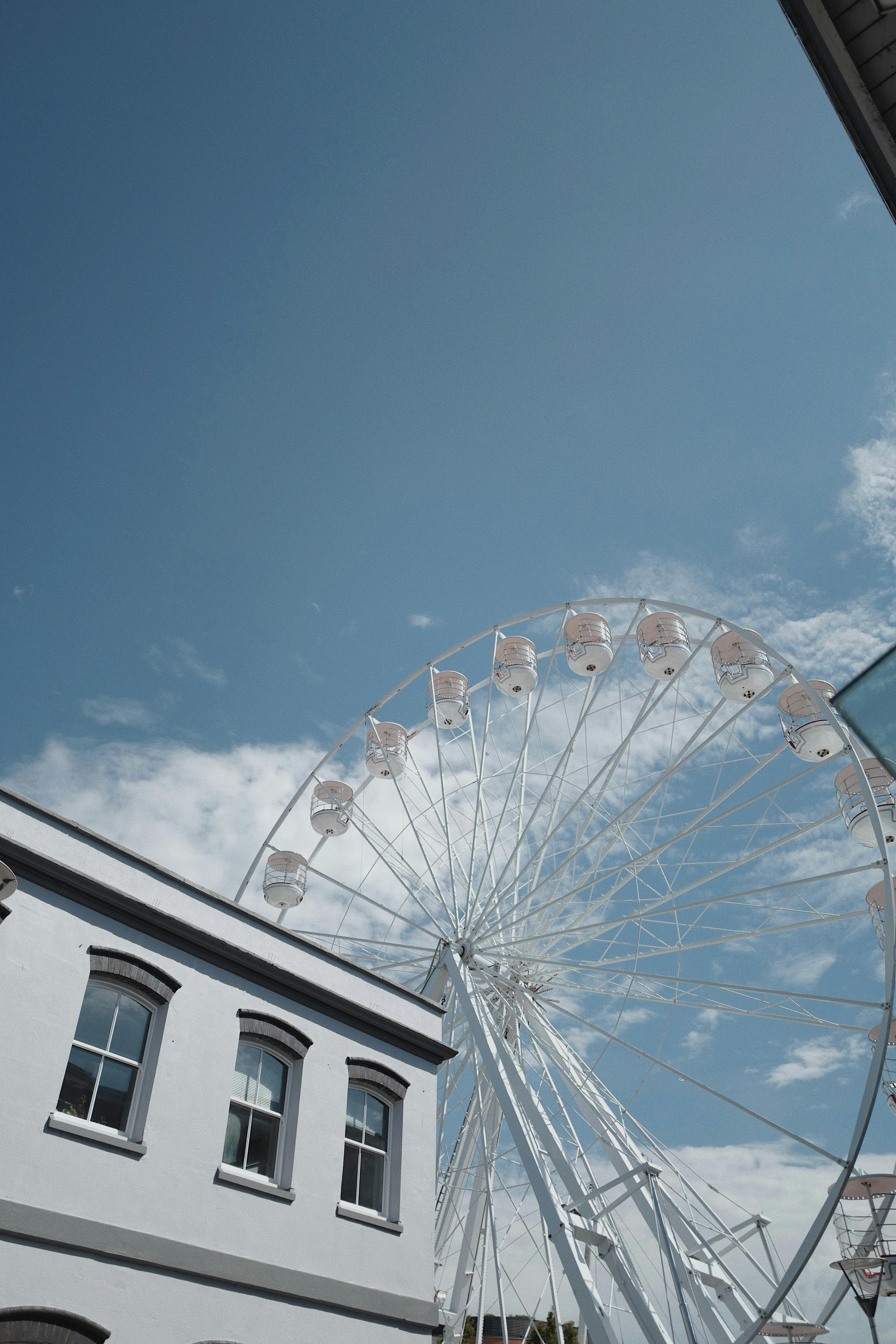 Low angle view of a Ferris wheel near a building under a clear blue sky.