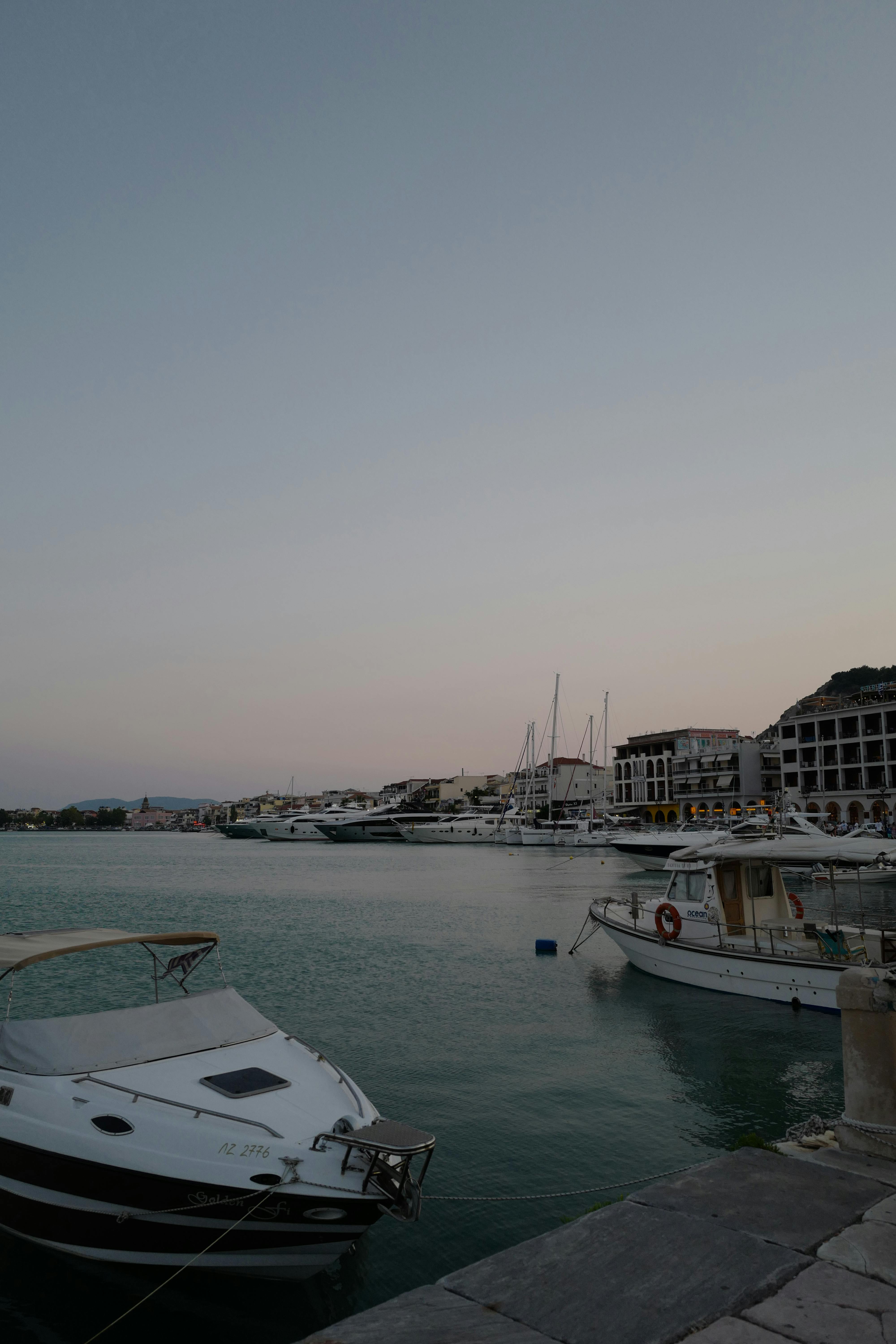 A serene scene of boats docked at a harbor under a dim, gray sky, reflecting tranquility and calm.