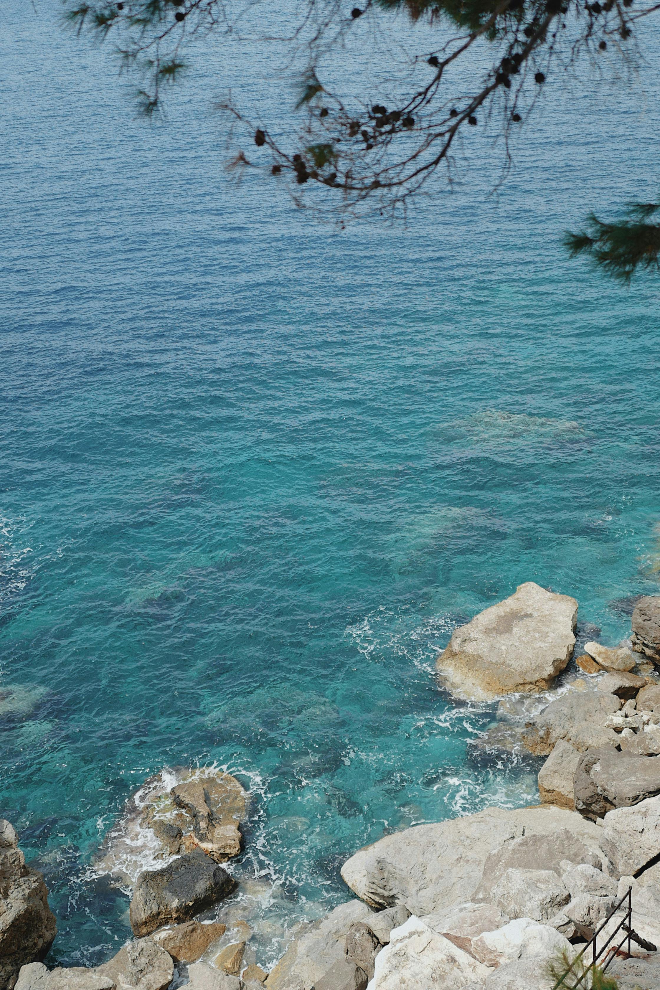 Scenic view of turquoise waters meeting rocky coastline under a clear sky.