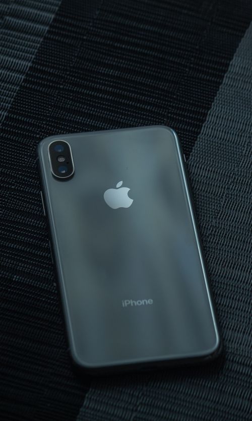 Free Close-up of a sleek iPhone on a textured dark surface, highlighting its design. Stock Photo