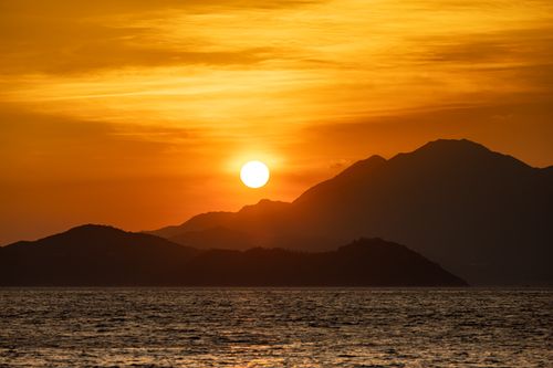 Free Stunning sunset view over a mountainous coastline, capturing the beauty of nature and serene sea. Stock Photo