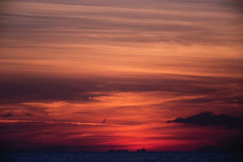 Free Stunning sunset over the ocean, showcasing vibrant red and orange hues in the sky. Stock Photo
