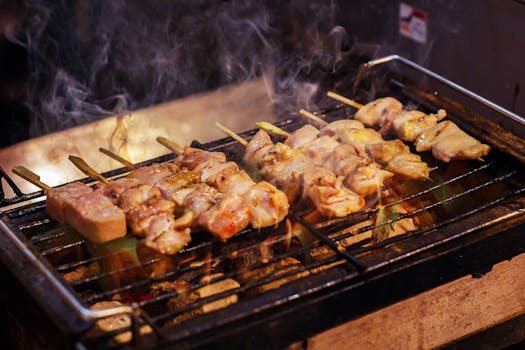 Delicious grilled chicken skewers sizzling with smoke and flame on a barbecue grill.