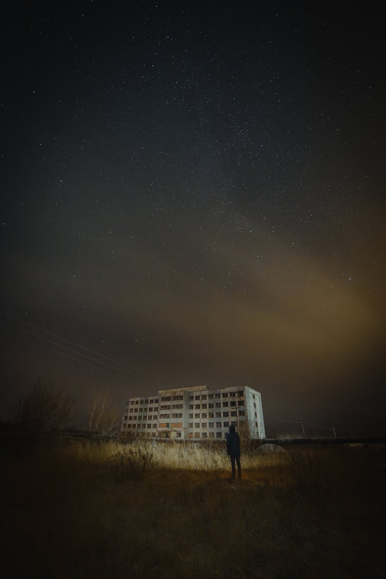 Person Near Wall And Abandoned Building At Night