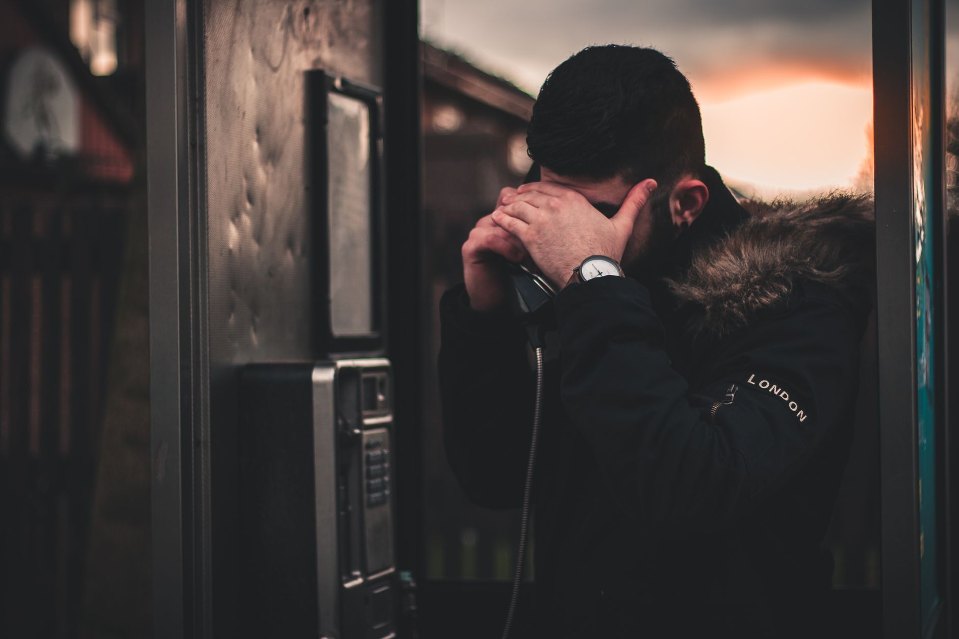 Young man staring at his phone in low light, hesitating before submitting his photo to be rated by strangers