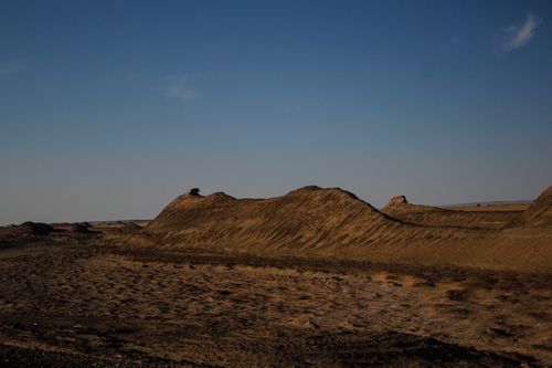 Free Scenic view of a sunlit desert with rolling hills under a clear blue sky. Stock Photo