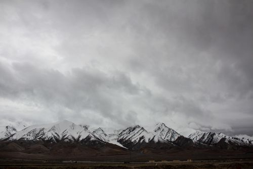 Free Snow-capped mountains under a cloudy sky create a gloomy wilderness scene. Stock Photo