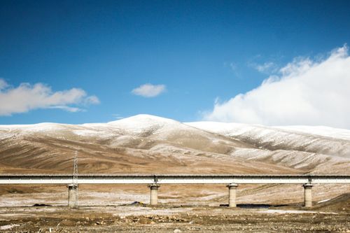 Free A serene winter mountain landscape with a bridge under a blue sky, ideal for nature and travel themes. Stock Photo