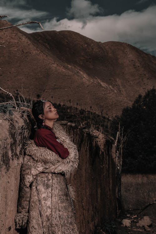 Brunette Woman in Coat Standing by Wall in Tibet