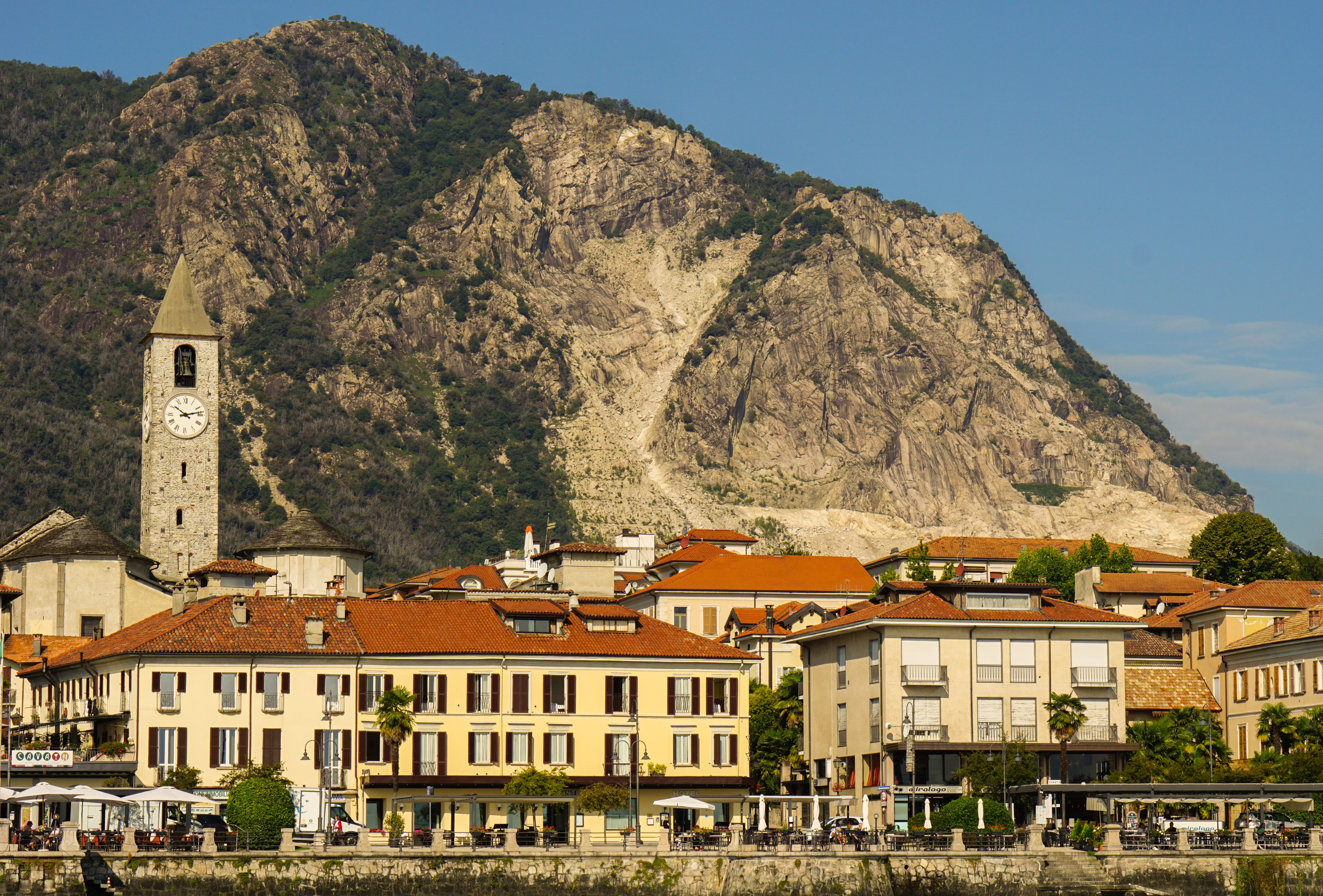 Beautiful Italian village with clock tower and mountain landscape, showcasing traditional architecture.