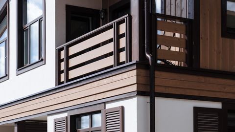 Contemporary suburban house exterior with wooden accents and shutters.