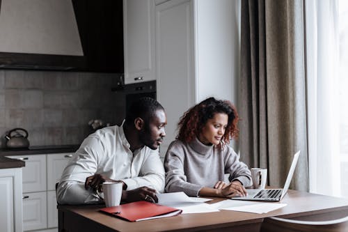 A Couple Working in Kitchen on a Laptop 