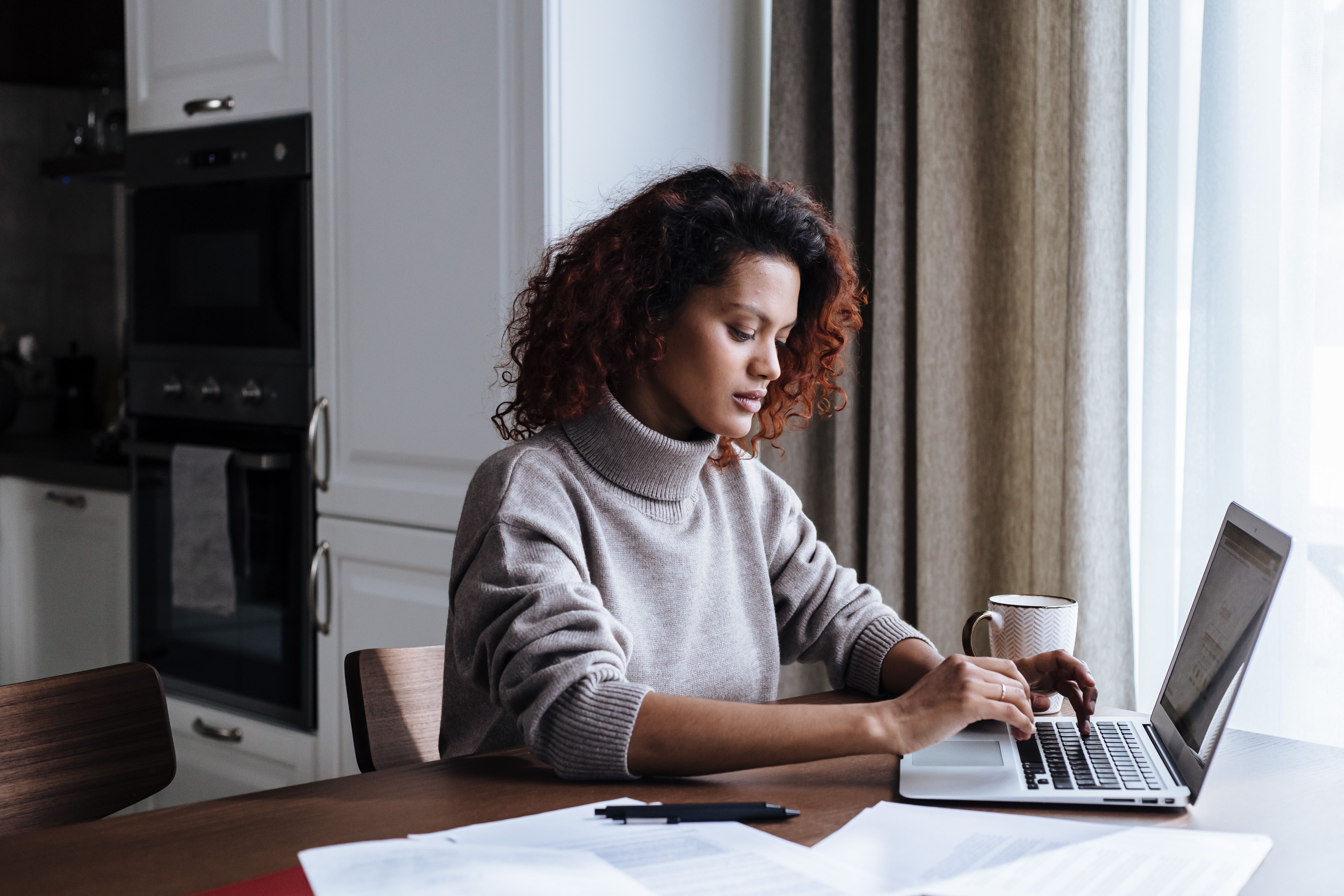 Homeowner researching pressure washing contractors on laptop at kitchen table