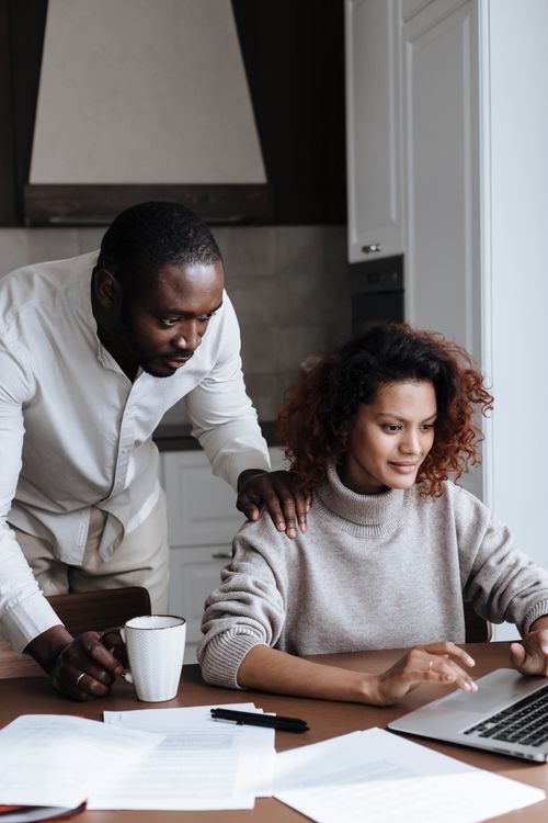 Free A diverse couple collaborates on a laptop in their cozy kitchen setting, enjoying a productive morning. Stock Photo