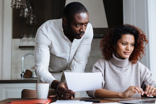 Free A diverse man and woman collaborating on a laptop in a stylish home kitchen. Stock Photo