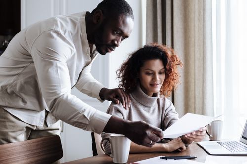Free A couple working together at home, reviewing documents with a laptop and coffee. Stock Photo