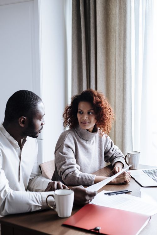 Free A couple engaging in a casual home office meeting, using a laptop, with coffee cups on the table. Stock Photo