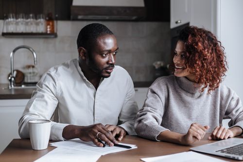 Free Black couple collaborating on a project at their kitchen table, showcasing teamwork and home office lifestyle. Stock Photo