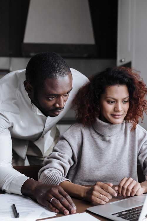 Free A diverse couple working together on a laptop in a cozy home setting, showcasing teamwork and technology. Stock Photo
