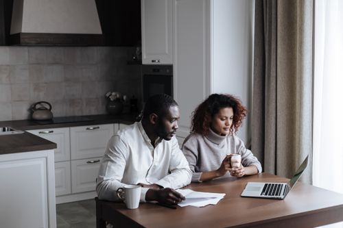 Free A couple working together on a laptop in their cozy kitchen, morning light. Stock Photo