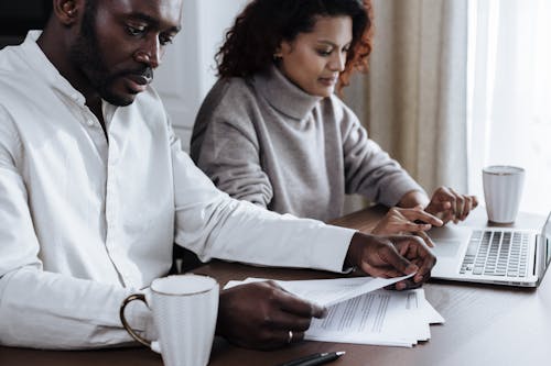 Free A diverse couple working together on a laptop at home, focused on collaboration and productivity. Stock Photo