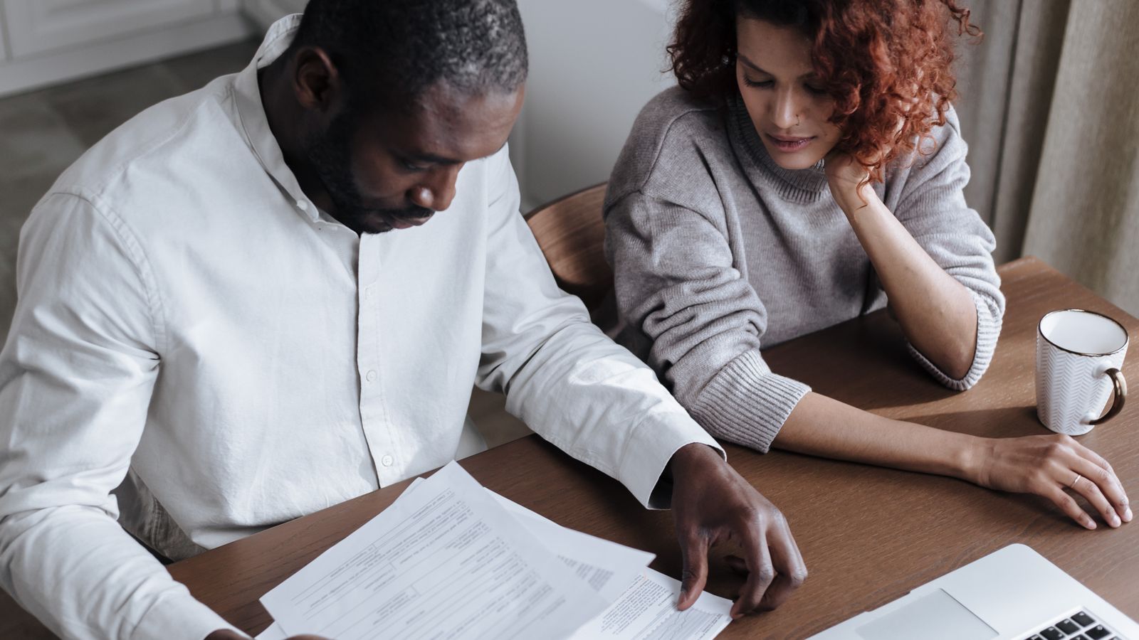 Two people reviewing papers together at a wooden table
